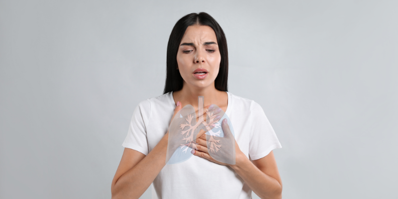 Silhouette of a person with highlighted lungs and warning icon, representing sudden shortness of breath as a possible heart attack symptom.